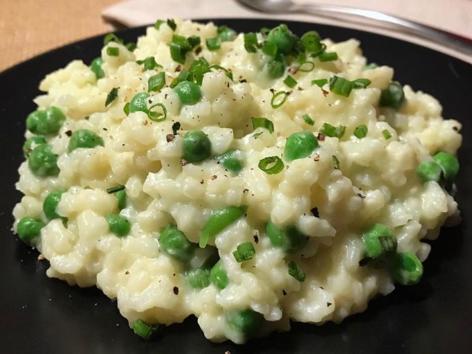 Cheesy risotto with peas and green onion on top