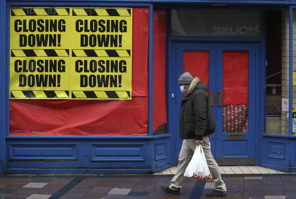 A man wearing a face mask to protect against coronavirus, walks past a closed shop in Stirling, Scotland, Sunday, Nov. 15, 2020. Scotland are currently using a tier system to try and drive down coronavirus cases. (Andrew Milligan/PA via AP)