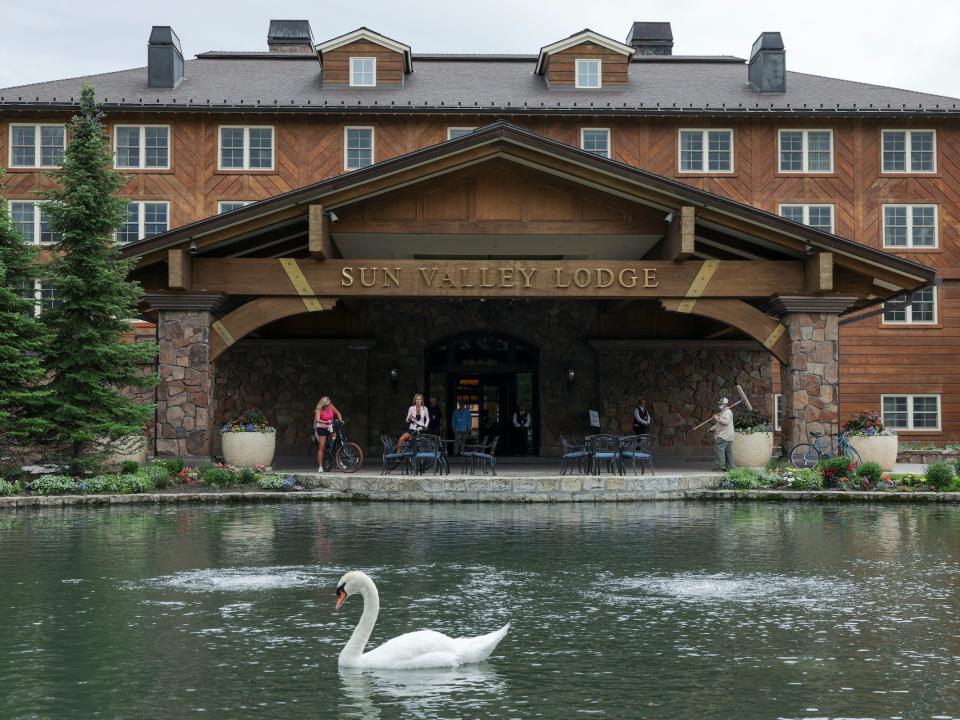 People stand outside the Sun Valley Lodge entrance where swans swim in pond