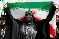 <p>An Iranian pro-government woman holds the Iranian flag during a rally against the recent protest gatherings in Iran, after the Friday prayer ceremony in Tehran, Iran September 23, 2022. Iranians have staged mass protests over the case of Mahsa Amini, 22, who died last week after being arrested by the morality police for wearing "unsuitable attire". Majid Asgaripour/WANA (West Asia News Agency) via REUTERS </p> 