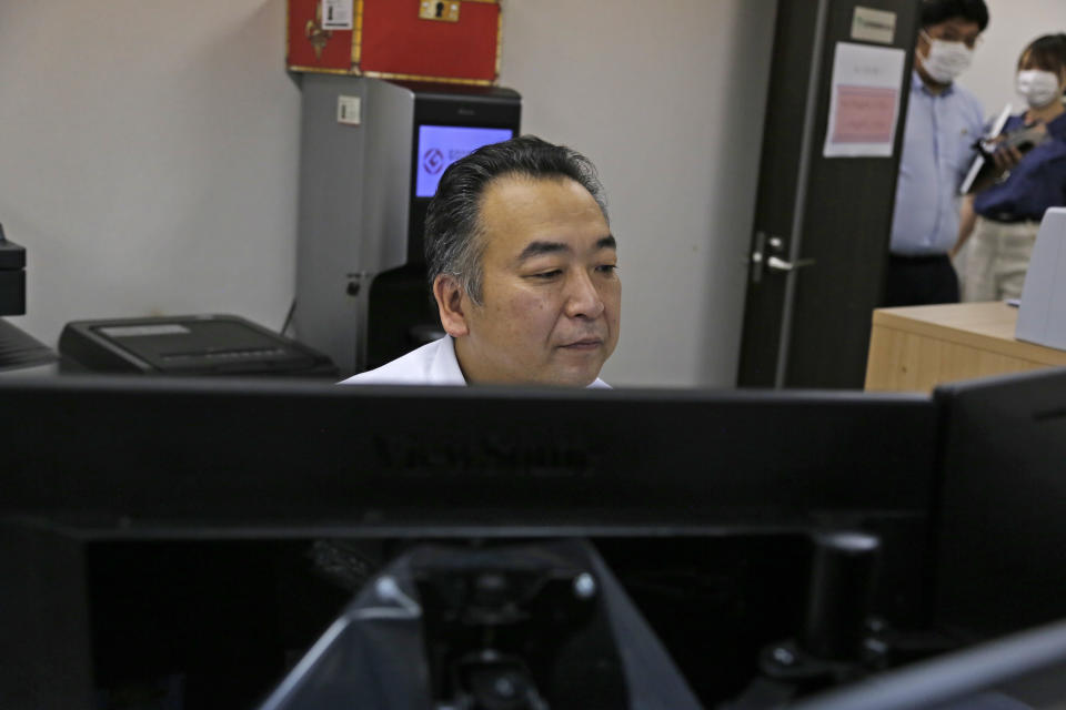 General Manager Tomohiko Kojima works at his desk at the Tokyo headquarters office of Daikyo Security Co. in Tokyo Monday, Aug. 22, 2022. They’re your run-of-the-mill Japanese “salarymen,” but the chief executive and general manager at a tiny Japanese security company are among the nation’s biggest TikTok stars, drawing 2.7 million followers and 54 million likes, and honored with awards as a trend-setter on the video-sharing app. (AP Photo/Yuri Kageyama)