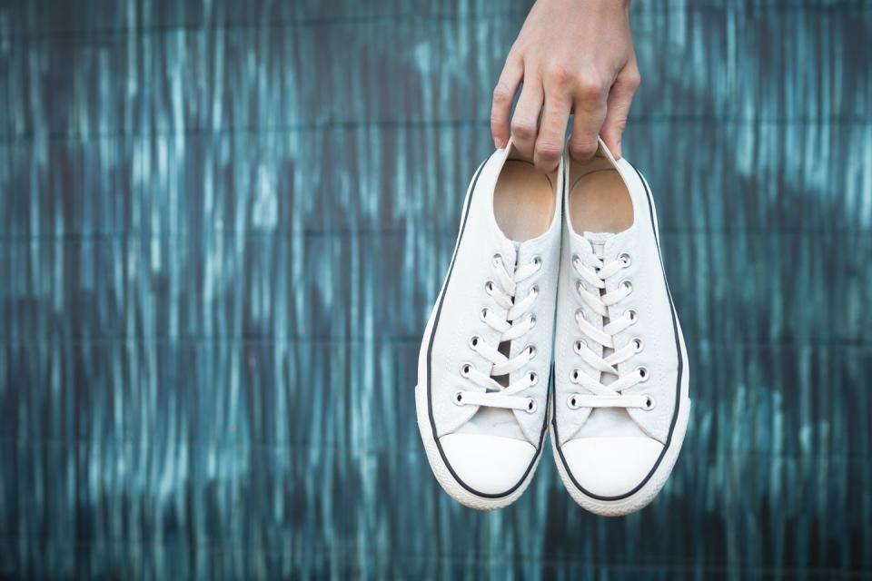 how to clean white shoes, hand holding a pair of shoes