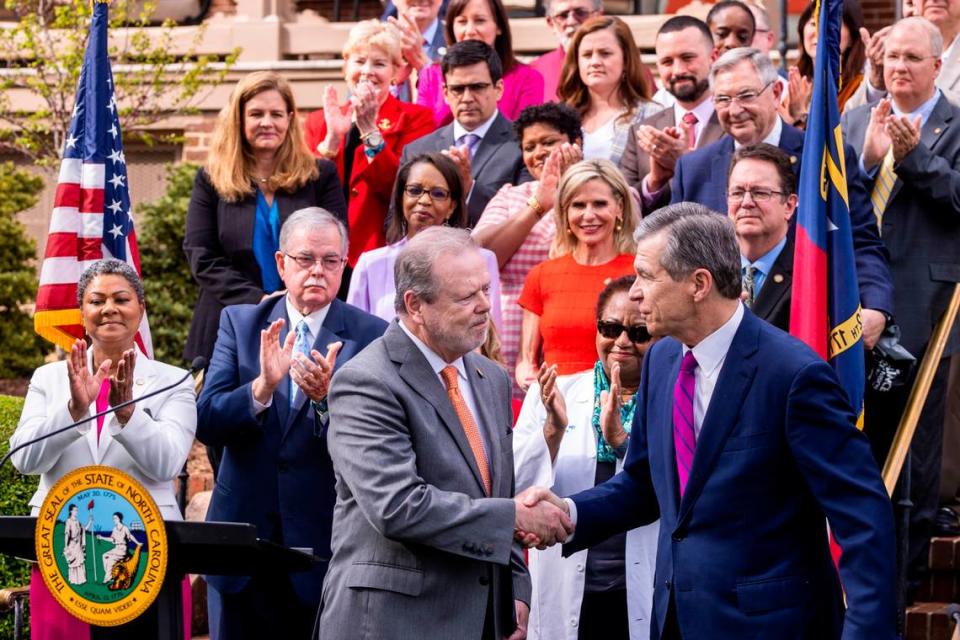 N.C. Gov. Roy Cooper, right, shakes hands with Senate Leader Phil Berger, left, before signing a Medicaid expansion bill into law during a ceremony at the Executive Mansion Monday, March 27, 2023.