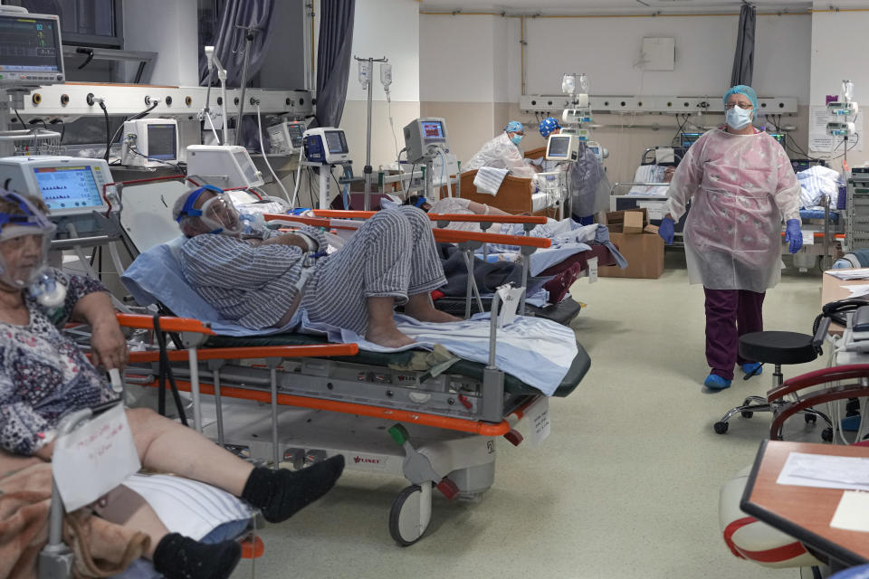 A member of the medical staff walks in a crowded COVID-19 isolation room at the University Emergency Hospital in Bucharest, Romania, Friday, Oct. 22, 2021. In Romania, a European Union country of around 19 million, only 35% of adults are fully inoculated against COVID-19 compared to an EU average of 74%.(AP Photo/Vadim Ghirda)