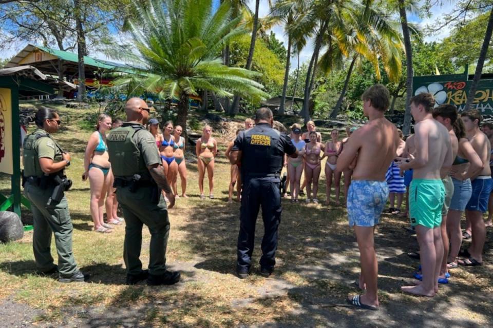 Enforcement officers from Hawaii’s Department of Land and Natural Resources speaking to swimmers in Honaunau, Hawaii (AP)