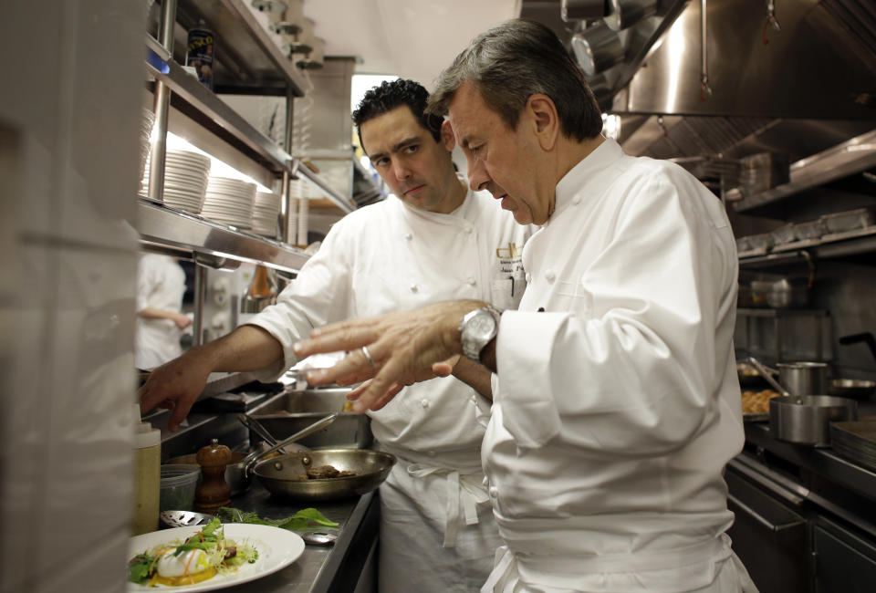 Chef Daniel Boulud, right, talks with executive chef Jason Pringle, left, as they prepare a Modern Salad Lyonnaise made of leek, lardon and oeuf mollet, at the db Bistro Moderne restaurant, Saturday, Feb. 22, 2014, in Miami. Boulud has an international food empire that includes more than a dozen restaurants and nearly as many cookbooks. Boulud hosted an exclusive lunch and book signing Saturday during the South Beach Wine and Food Festival. (AP Photo/Lynne Sladky)