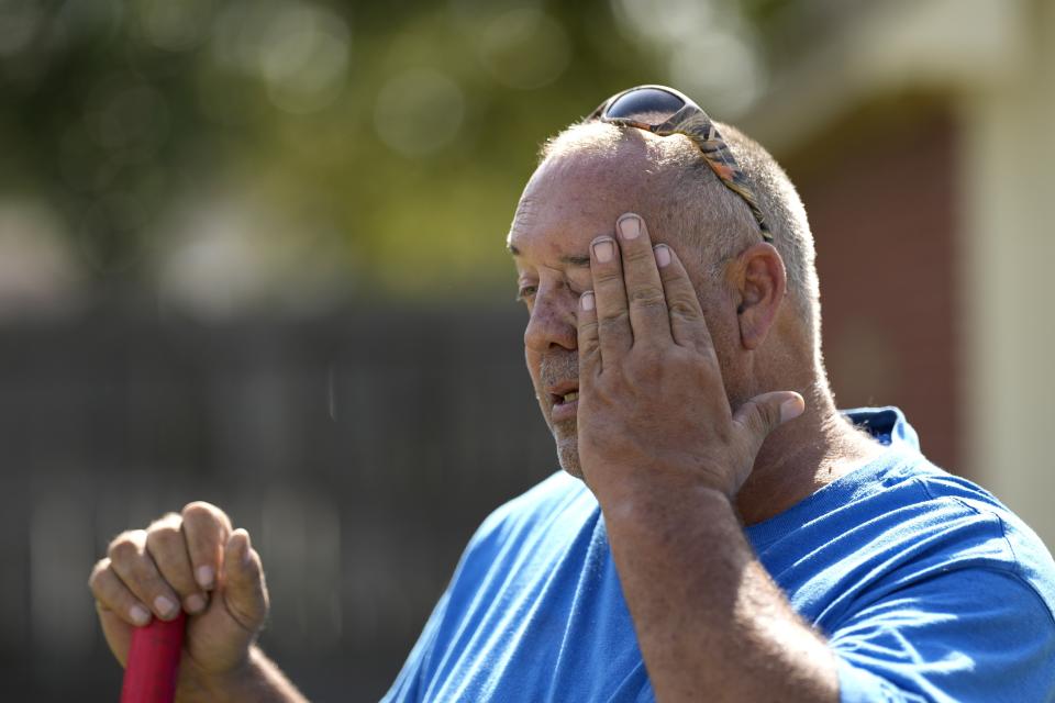 Robert Harris pauses to wipes his face while digging fence post holes in Houston