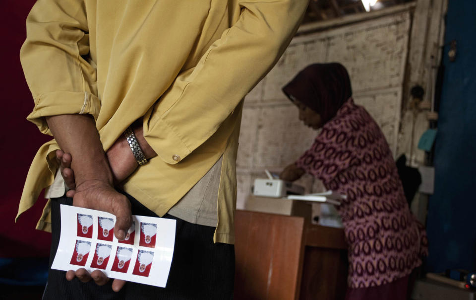 A customer holds a contact sheet as armless professional photographer Rusidah, 44, prints images on March 13, 2012 in Purworejo, Indonesia. (Photo by Ulet Ifansasti/Getty Images)