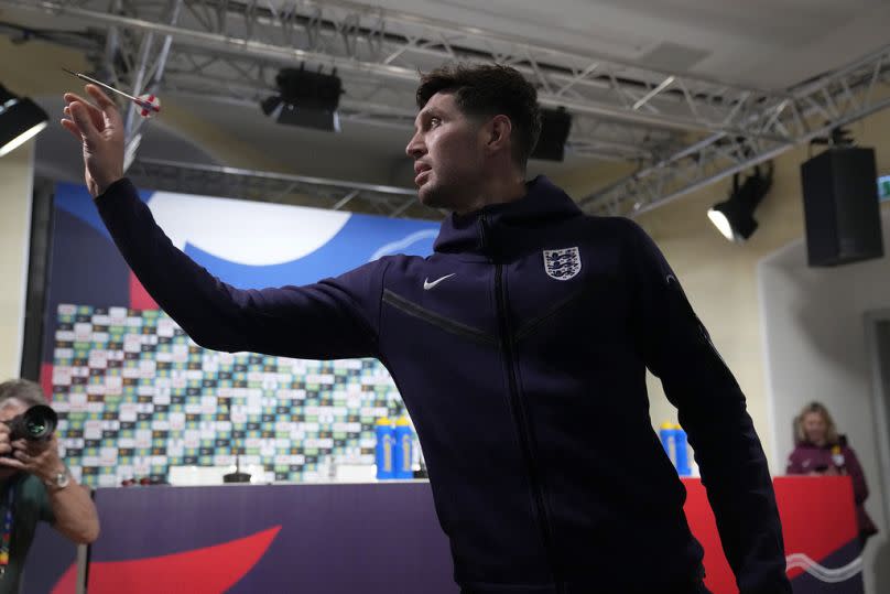 John Stones, de Inglaterra, juega dardos contra un periodista antes de una conferencia de prensa en Blankenhain, Alemania, el jueves 4 de julio de 2024.