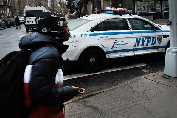 People walk past a police car in the in the Brownsville neighborhood of Brooklyn on November 18, 2019 in New York City. (Photo by Spencer Platt/Getty Images)