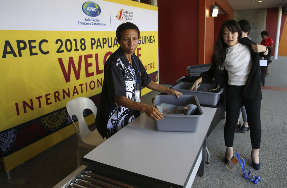 A woman goes through a security check at the APEC 2018 International Media Center at Port Moresby, Papua New Guinea Wednesday, Nov. 14, 2018. After three decades of promoting free trade as a panacea to poverty, the APEC grouping of nations that includes the U.S. and China is holding its lavish annual leaders meeting in the country that can least afford it. (AP Photo/Aaron Favila)