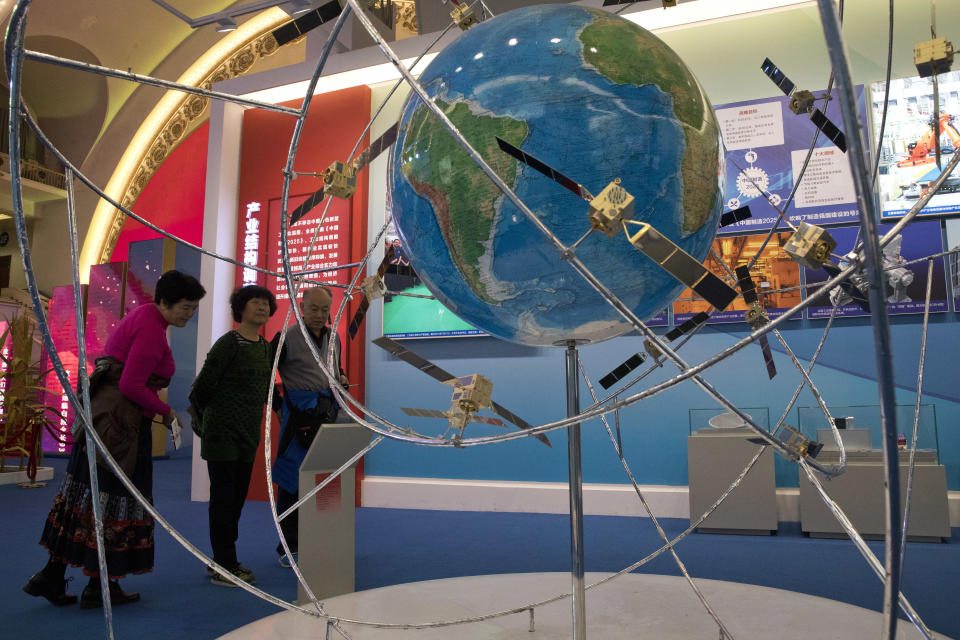 FILE - In this Oct. 19, 2017, file photo, visitors look at a display of satellite technologies at an exhibition highlighting China's achievements under five years of President Xi Jinping's leadership at the Beijing Exhibition Hall in Beijing. China on Tuesday, June 23, 2020 launched the final satellite in its Beidou constellation that emulates the U.S. Global Positioning System, marking a further step in the country's advance as a major space power. (AP Photo/Ng Han Guan, File)