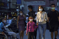 People wearing face masks to protect against the coronavirus, walk along a street in Hong Kong, Monday, Nov. 30, 2020. (AP Photo/Kin Cheung)