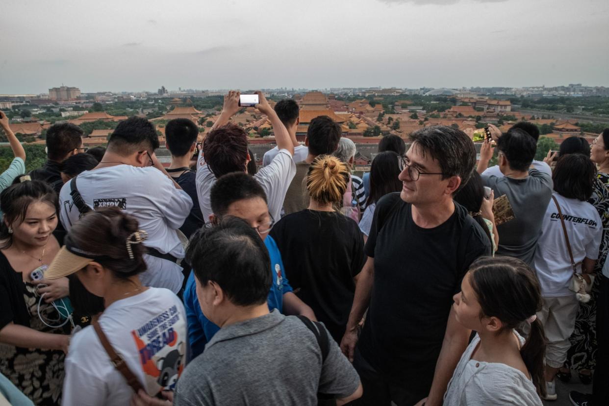 A French tourist stands among a crowd of Chinese tourists gathered to see the Forbidden City at sunset in Beijing on Aug. 12.