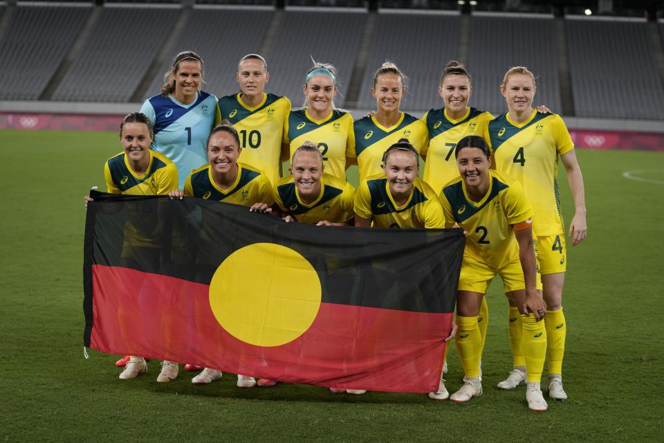 Australia players pose for a group photo with an indigenous flag prior to women's soccer match against New Zealand at the 2020 Summer Olympics, Wednesday, July 21, 2021, in Tokyo. (AP Photo/Ricardo Mazalan)