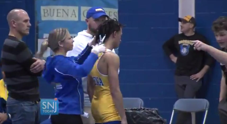 In this image taken from a Wednesday, Dec. 19, 2018 video provided by SNJTODAY.COM, Buena Regional High School wrestler Andrew Johnson gets his hair cut courtside minutes before his match in Buena, N.J., after a referee told Johnson he would forfeit his bout if he didn't have his dreadlocks cut off. Johnson went on to win the match after a SNJ Today reporter tweeted video if the incident, the state's Interscholastic Athletic Association says they are recommending the referee not be assigned to any event until the matter has been reviewed more thoroughly. (Michael Frankel/SNJTODAY.COM viavAP)