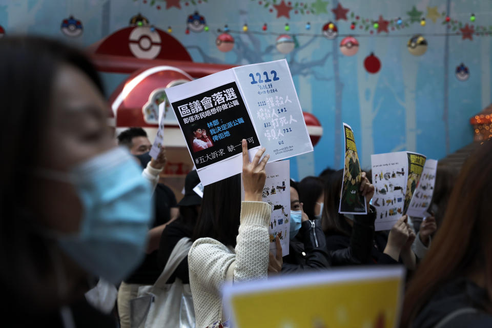 Pro-democracy protesters and office workers stage a lunch time protests at Causeway Bay in Hong Kong, Wednesday, Dec. 11, 2019. Hong Kong Chief Executive Carrie Lam on Tuesday again ruled out further concessions to protesters who marched peacefully in their hundreds of thousands this past weekend, days before she is to travel to Beijing for regularly scheduled meetings with Communist Party leaders. The placard in center carrying a photo of Hong Kong Chief Executive Carrie Lam reads "District Councils lost in election, means people don't want you in office. Five demands no one less". (AP Photo/Mark Schiefelbein)