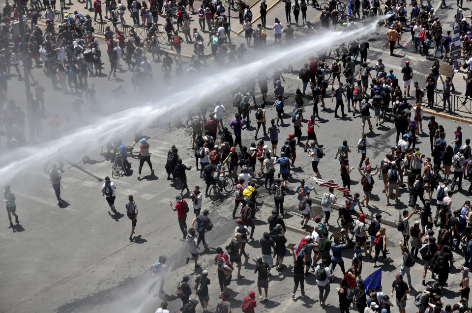 A police water cannon charges a crowd of anti-government demonstrators during a protest in Santiago, Chile, Tuesday, Oct. 22, 2019. Chile has been facing days of unrest, triggered by a relatively minor increase in subway fares. The protests have shaken a nation noted for economic stability over the past decades, which has seen steadily declining poverty despite persistent high rates of inequality. (AP Photo/Esteban Felix)