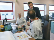 French President Emmanuel Macron shakes hands with an employee as he visits the plant of British-Swedish pharmaceutical group Astrazeneca in Dunkirk, northern France, Monday, Jan. 20, 2020. French President Emmanuel Macron is hosting 180 international business leaders later today at the Palace of Versailles in a bid to promote France's economic attractiveness despite over six weeks of crippling strikes over his government's planned pension changes.(Denis Charlet/Pool Photo via AP)