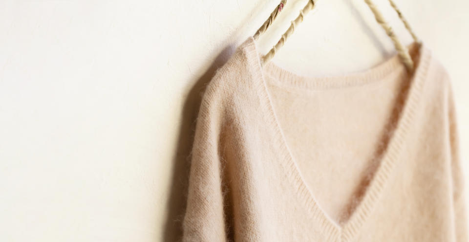 light pink sweater hanging on clothes hanger on white background.close up.