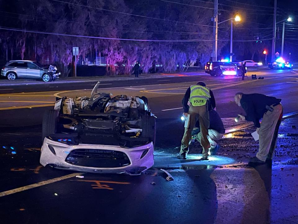 Ocala police officers examining one of two vehicles involved in a fiery wreck where two people were killed and a third injured along SE 36th Avenue on Tuesday night.