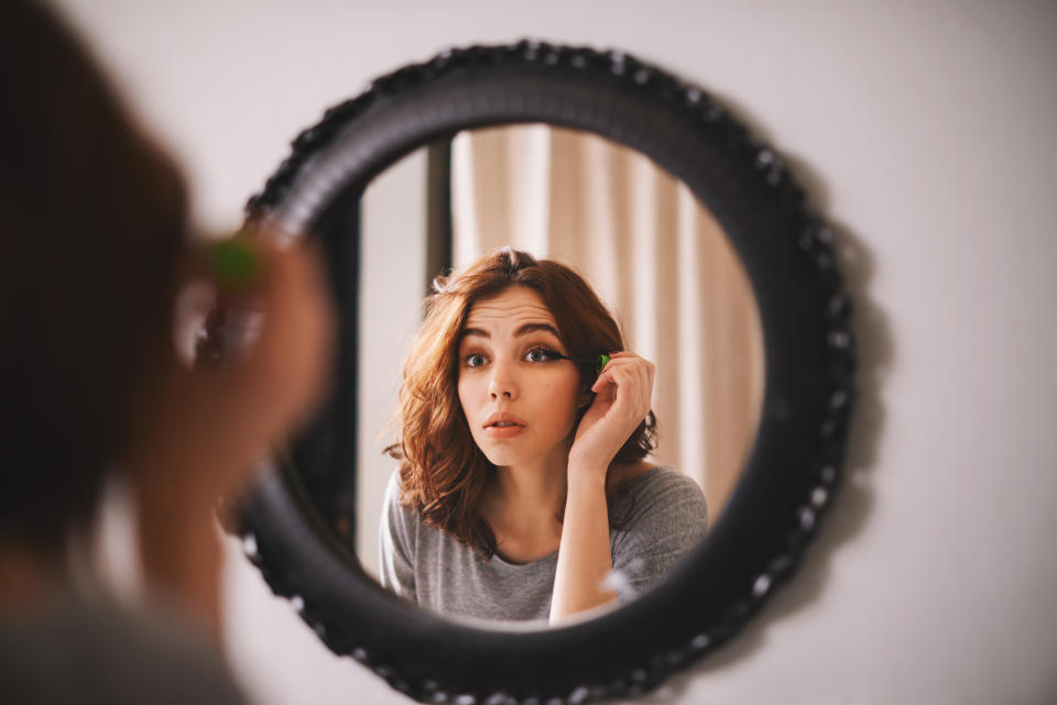 Cropped shot of a young woman putting on mascara