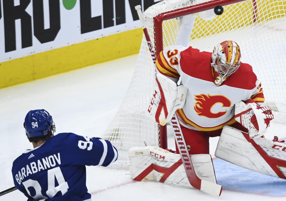 Calgary Flames goaltender David Rittich (33) gets a piece of a shot by Toronto Maple Leafs left wing Alexander Barabanov (94) during third period NHL hockey action in Toronto on Monday, Feb. 22, 2021. (Nathan Denette/The Canadian Press via AP)