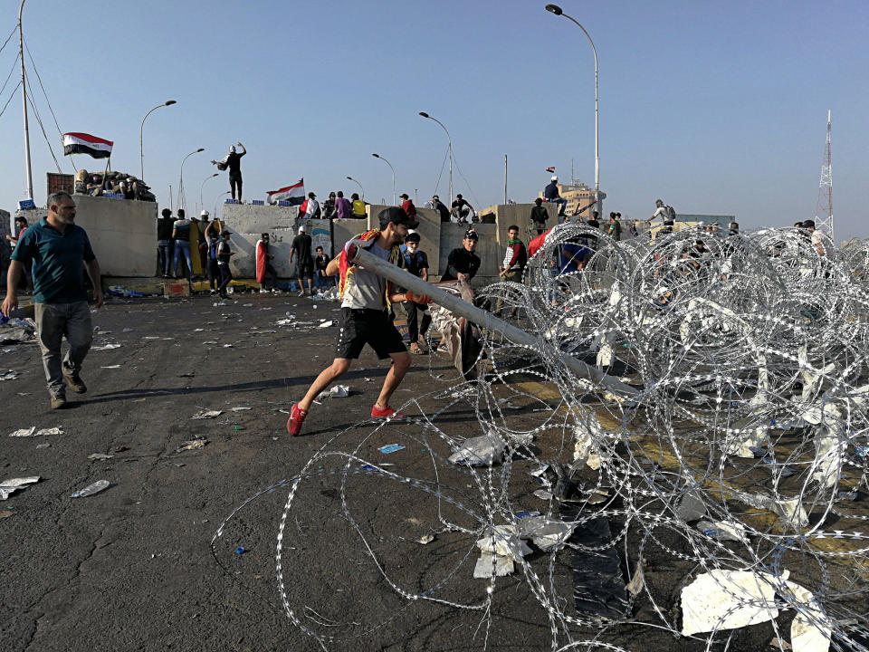 Iraqi anti-government protesters take control of concrete walls and barriers set by security forces that closes the Al-Sanak Bridge leading to the Green Zone, during a demonstration in Baghdad, Iraq, Thursday, Oct. 31, 2019. Late Wednesday, hundreds of people headed to the Al-Sanak Bridge that runs parallel to the Joumhouriya Bridge, opening a new front in their attempts to cross the Tigris River to the Green Zone. Security forces fired volleys of tear gas that billowed smoke and covered the night sky. (AP Photo/Hadi Mizban)