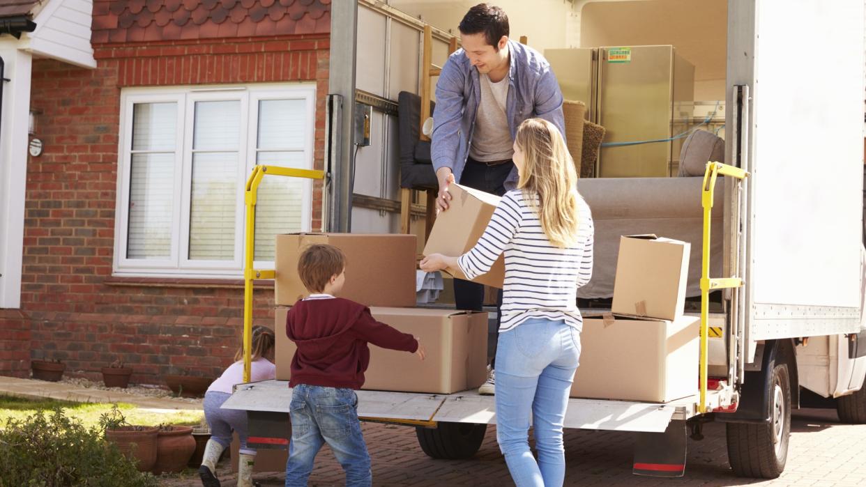 Family Unpacking Moving In Boxes From Removal Truck.