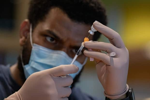 Pharmacy technician Heron Roach prepares a dose of the Pfizer-BioNTech COVID-19 vaccine at a temporary clinic at the Woodbine racetrack and casino, in northeast Toronto, on May 5, 2021. (Evan Mitsui/CBC - image credit)