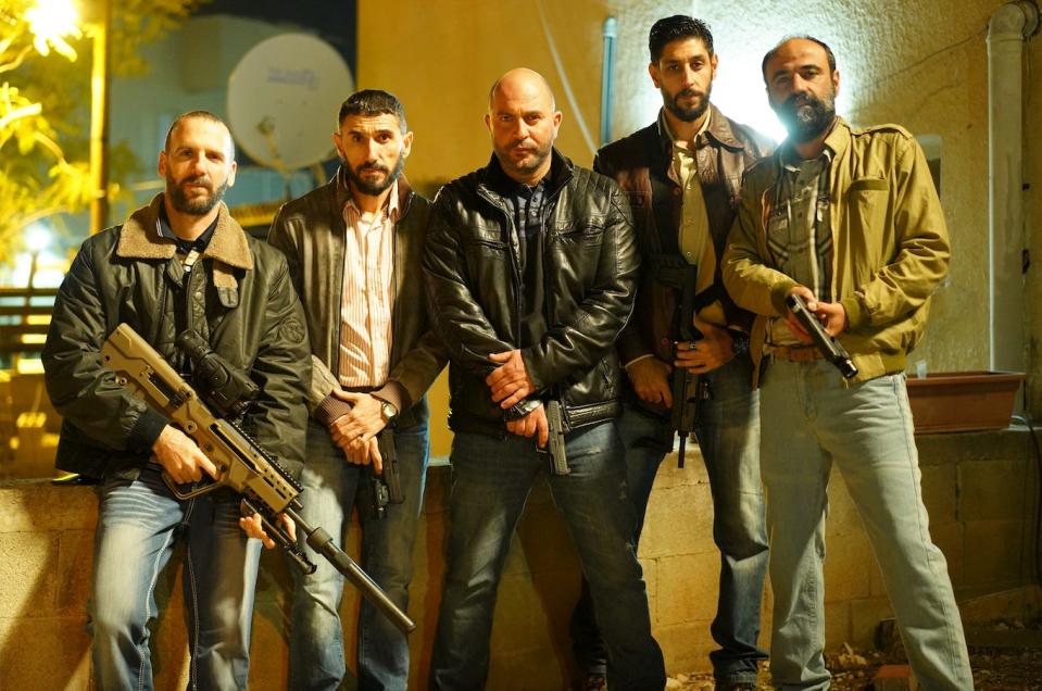 the cast of fauda, the netflix show. five men in heavy leather jackets, carrying a mix of handguns and rifles