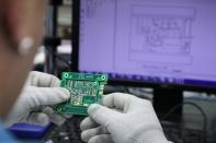 Employee of the automated test equipment designer and solutions provider Aemulus Holdings Berhad inspects a printed circuit board at a production facility in Penang