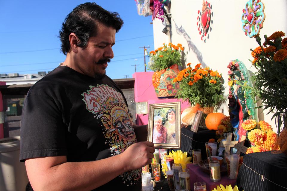 ET Rivera, owner of Tres Leches Cafe, holds up a photo of his great-grandmother (left) and grandmother, who is still alive, at the cafe's Dia de los Muertos community ofrenda on Oct. 17, 2019.
