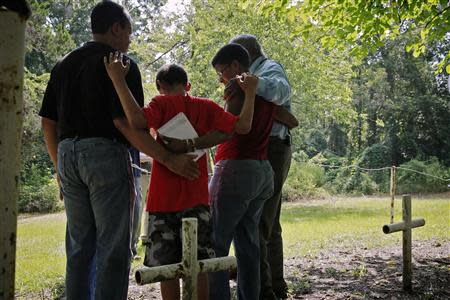 L-R: Steven Barnes, 61, of Smyrna, Georgia, his son Jason Due-Barnes, 9, wife Tananarive Due, 47, and her father John Due, 78, of Atlanta, Georgia, embrace during a memorial ceremony at the Boot Hill cemetery at the now closed Arthur G. Dozier School for Boys in Marianna, Florida, August 31, 2013. REUTERS/Edmund D Fountain/Pool