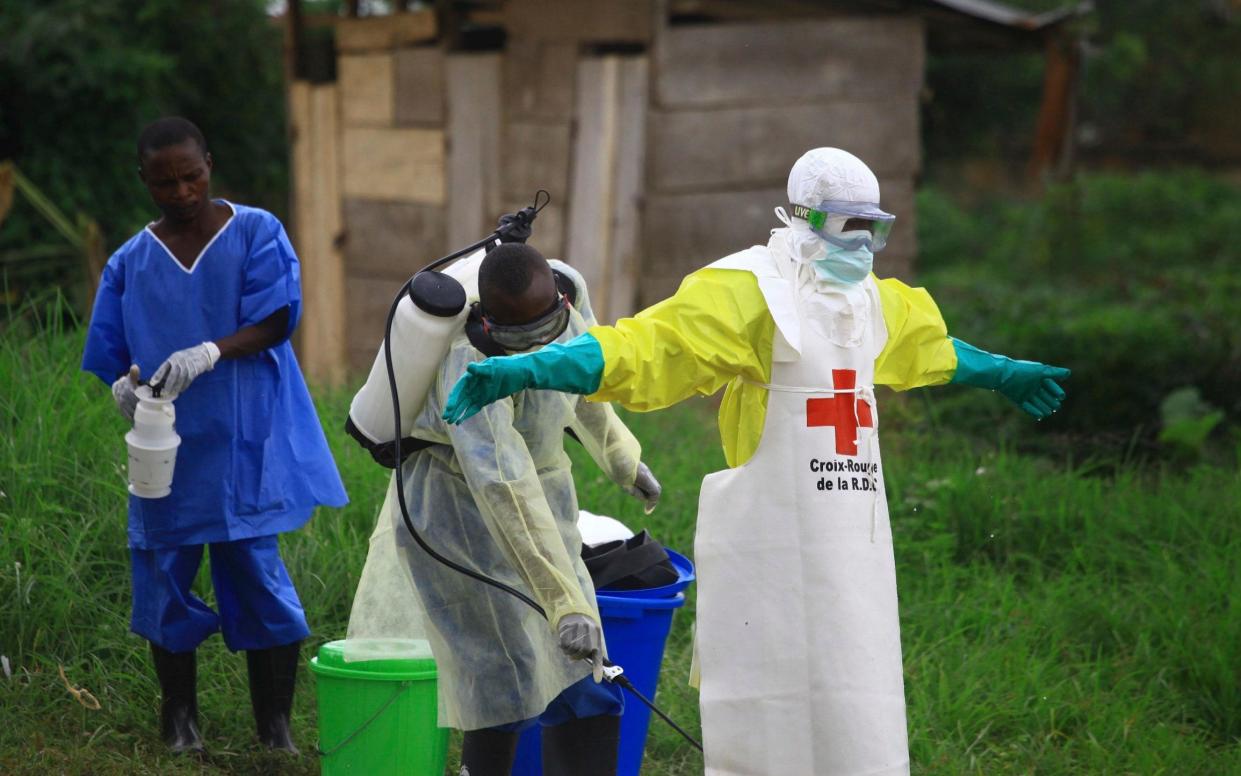 A health worker sprays disinfectant on a colleague at an Ebola treatment centre in Beni, eastern Congo - AP