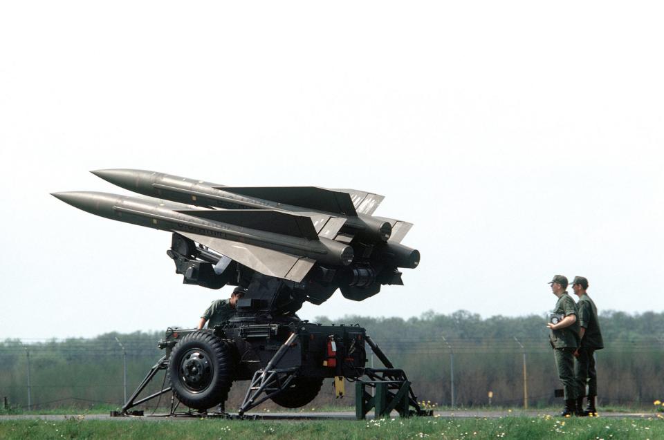 Soldiers looking at large missiles.