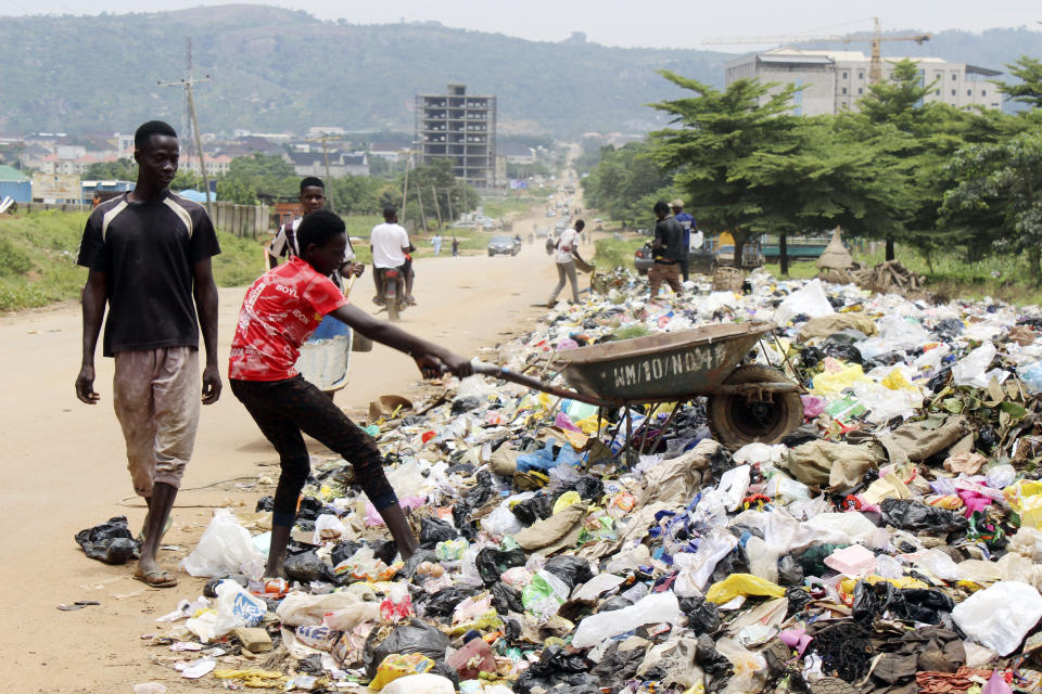 A boy empties garbage onto the street in Abuja, Nigeria, Friday, Sept. 3, 2021. Nigeria is seeing one of its worst cholera outbreaks in years, with more than 2,300 people dying from suspected cases as the West African nation struggles to deal with multiple disease outbreaks. This year’s outbreak which is associated with a higher case fatality rate than the previous four years is also worsened by what many consider to be a bigger priority for state governments: the COVID-19 pandemic. (AP Photo/Gbemiga Olamikan)