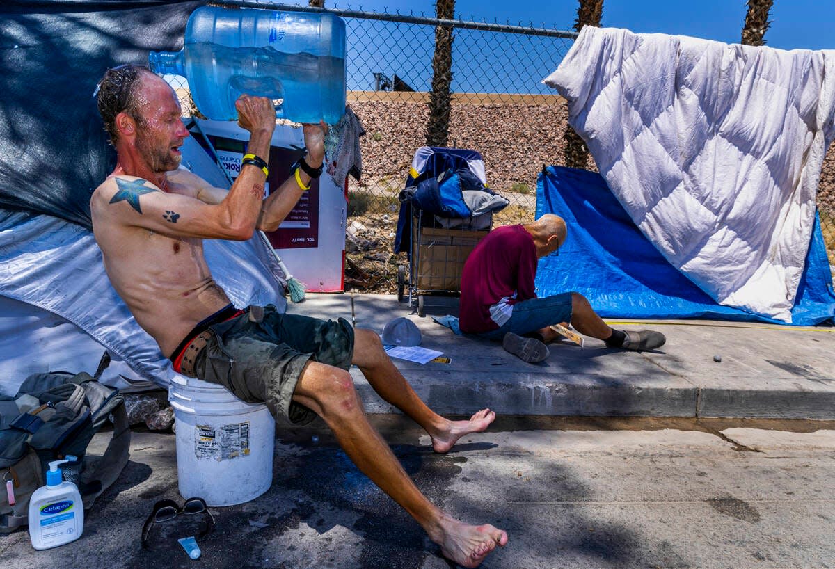 Homeless man Milton John Scott III pours a jug of water on his head to escape the heat and wash up about his shelter along North A Street as Vegas Stronger's Street Team is out offering services including a list of cooling stations on Wednesday, June 5, 2024, in Las Vegas.