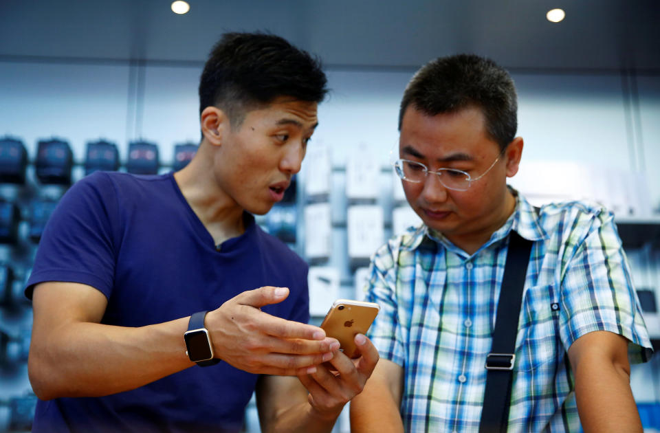 A staff member (L) explains Apple's new iPhone 7 to a customer at an Apple store in Beijing, China, September 16, 2016. REUTERS/Thomas Peter