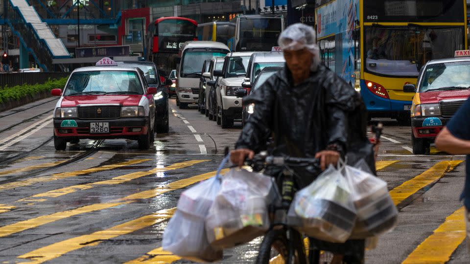 A delivery man cycles along a road as cars wait for a traffic light to change, in Hong Kong, China on May 24, 2024. - Noemi Cassanelli/CNN