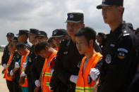 Chinese nationals (in orange vests) who were arrested over a suspected internet scam, are escorted by Chinese police officers before they were deported at Phnom Penh International Airport, in Phnom Penh, Cambodia, October 12, 2017. REUTERS/Samrang Pring