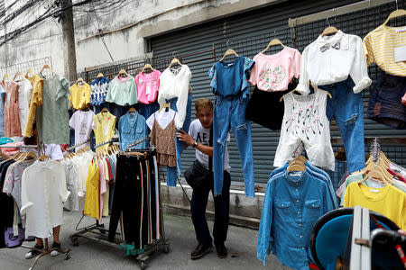 A street vendor holds his clothes when police take action on a street in Bangkok, Thailand, September 12, 2018. REUTERS/Soe Zeya Tun