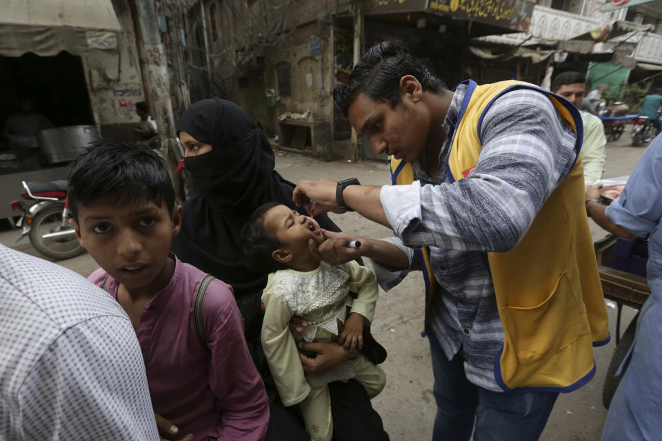 A health worker gives polio vaccines to children in a neighborhood of Lahore, Pakistan, Monday, May 23, 2022. Pakistan launched a new anti-polio drive on Monday, more than a week after officials detected the third case so far this year in the country's northwestern region bordering Afghanistan. (AP Photo/K.M. Chaudary)