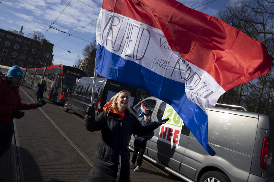 A woman dances next to a sign reading "2G NO" with a Dutch flag reading "Freedom for Our Children" as some 20 trucs blocked one entrance to the government buildings in The Hague, Netherlands, Saturday, Feb. 12, 2022, to protest against COVID-19 restrictions. The events are in part inspired by protesters in Canada. (AP Photo/Peter Dejong)