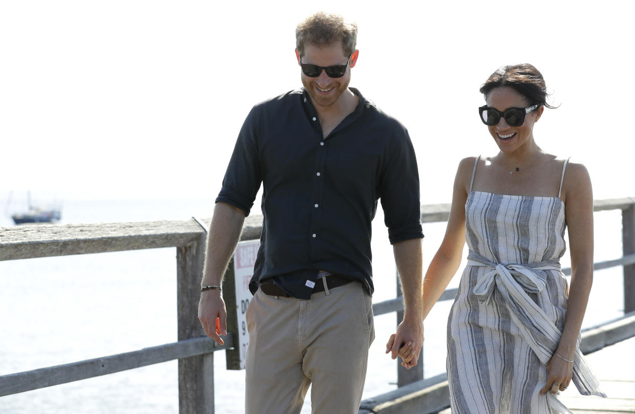 Britain's Prince Harry, left, and Meghan, Duchess of Sussex walk along Kingfisher Bay Jetty during a visit to Fraser Island, Australia, Monday, Oct. 22, 2018. Prince Harry and his wife Meghan are on day seven of their 16-day tour of Australia and the South Pacific. (AP Photo/Kirsty Wigglesworth, Pool)