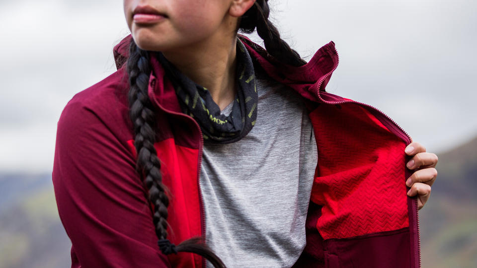 A woman wearing a Patagonia Women’s R1 CrossStrata Hoody holds the front open to show the texture of the fabric on the inside.