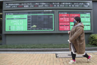 A woman walks by an electronic stock board of a securities firm in Tokyo, Monday, Jan. 27, 2020. Shares tumbled Monday in the few Asian markets open as China announced sharp increases in the number of people affected in an outbreak of a potentially deadly virus. (AP Photo/Koji Sasahara)