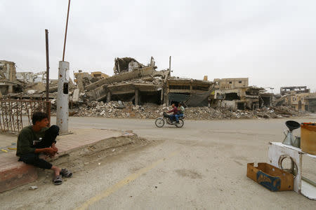 People ride on a motorbike past damaged buildings in Raqqa, Syria October 12, 2018. REUTERS/Aboud Hamam