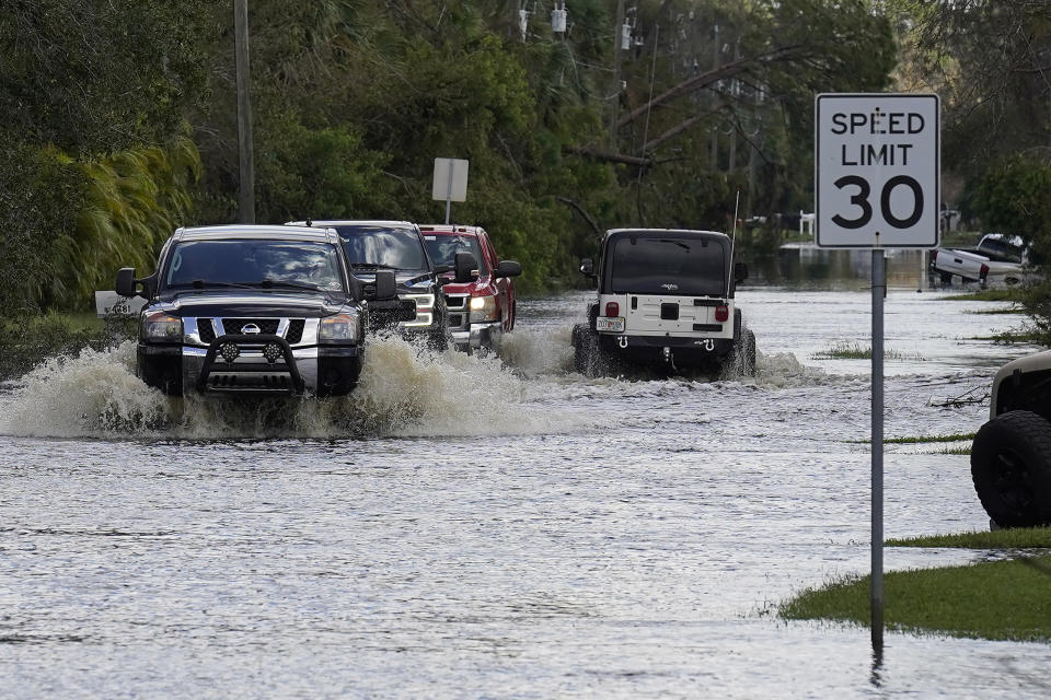 Residents drive through a flooded neighborhood Tuesday, Oct. 4, 2022, in North Port, Fla. Rivers overflowed their banks from the effects of Hurricane Ian when the storm made landfall last week along Florida's west coast. (AP Photo/Chris O'Meara)