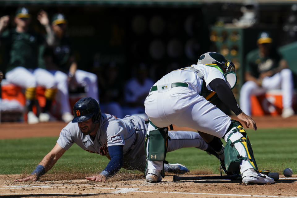 Detroit Tigers' Matt Vierling, left, scores next to Oakland Athletics catcher Carlos Pérez, right, on a throwing error by right fielder Brent Rooker during the third inning of a baseball game Sunday, Sept. 24, 2023, in Oakland, Calif. (AP Photo/Godofredo A. Vásquez)